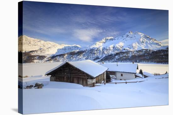 Huts and mountains covered in snow at sunset Spluga Maloja Canton of Graubunden Engadin Switzerland-ClickAlps-Stretched Canvas