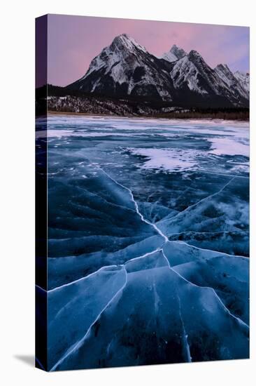 Ice cracks along Abraham Lake in Banff, Canada with purple clouds and scenic mountains-David Chang-Stretched Canvas