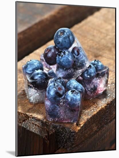 Ice Cubes with Blueberries on a Wooden Table-Chris Schäfer-Mounted Photographic Print