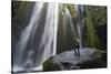 Iceland, Seljalandsfoss. Woman on large rock in front of streaming falls in green slot canyon. (MR)-Mark Williford-Stretched Canvas
