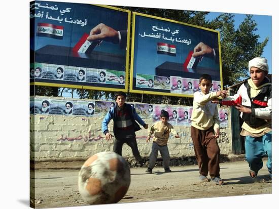 Iraqi Boys Play Soccer Below the Poster Reading "To Grant Iraqi Children Better Iraq"-null-Stretched Canvas