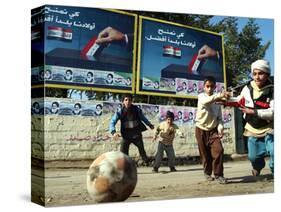 Iraqi Boys Play Soccer Below the Poster Reading "To Grant Iraqi Children Better Iraq"-null-Stretched Canvas