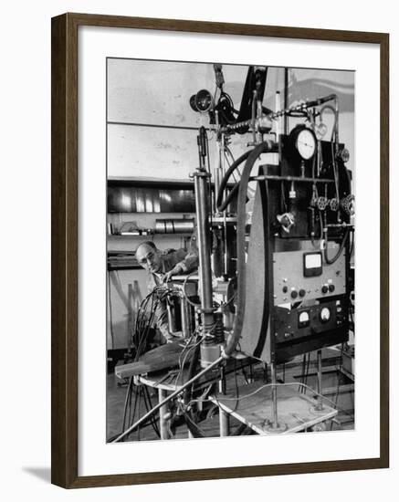 Italian Physicist Enrico Fermi Peering Out from Behind Large, Complicated Machinery in Laboratory-Ralph Morse-Framed Premium Photographic Print