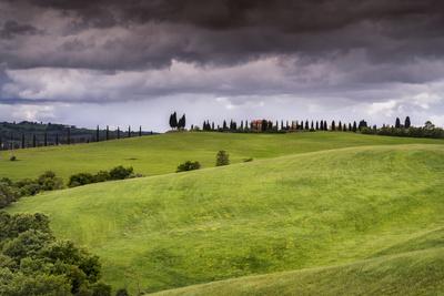 Europe, Italy, Tuscany, Val d Orcia. Farmland under stormy sky.