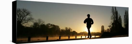 Jogger Silhouetted Against the Rising Sun as He Runs Past the Serpentine Lake in Hyde Park, London-null-Stretched Canvas