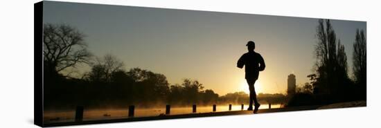 Jogger Silhouetted Against the Rising Sun as He Runs Past the Serpentine Lake in Hyde Park, London-null-Stretched Canvas