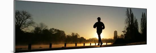 Jogger Silhouetted Against the Rising Sun as He Runs Past the Serpentine Lake in Hyde Park, London-null-Mounted Photographic Print