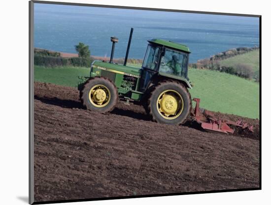 John Deere Tractor with a Rotivator on a Sloping Field in Spring, at Holcombe, Devon, England, UK-Ian Griffiths-Mounted Photographic Print