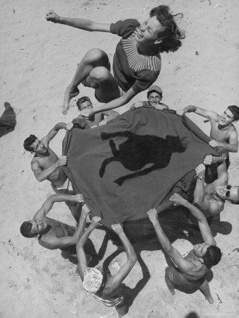 Teenaged Boys Using Blanket to Toss Their Friend, Norma Baker, Into the Air on the Beach
