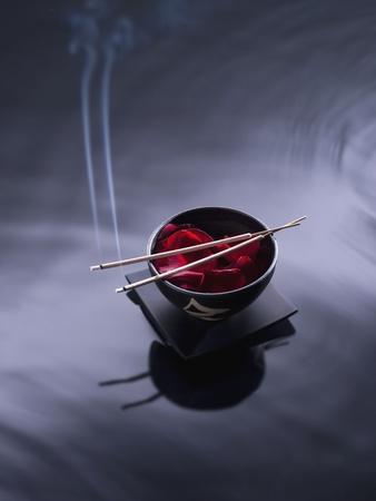Burning incense on top of bowl of petals