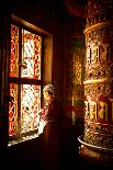 A Tibetan woman stands next to a large prayer wheel of the temple of Boudhanath Stupa, Kathmandu, N-Julian Bound-Framed Photographic Print