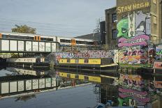 Overground train drives past canal by artists studios and warehouses in Hackney Wick, London, Engla-Julio Etchart-Photographic Print