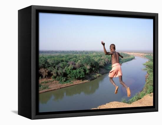 Karo Boy Leaps Off a Cliff Over the Omo River, Ethiopia-Janis Miglavs-Framed Stretched Canvas