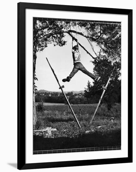 Kenneth Merriman Swinging on Tree Limb After Kicking Away Stilts-Robert W^ Kelley-Framed Photographic Print