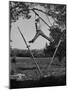 Kenneth Merriman Swinging on Tree Limb after Kicking Away Stilts-null-Mounted Photographic Print