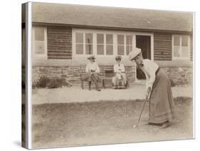 Lady Golfer Prepares to Putt as Two Seated Spectators Watch-null-Stretched Canvas