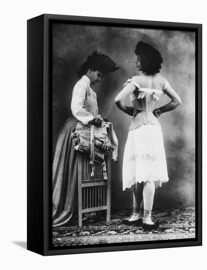 Lady Tries on a Corset While Another Woman Waits with Another One-null-Framed Stretched Canvas