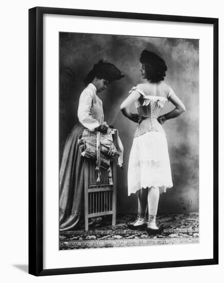 Lady Tries on a Corset While Another Woman Waits with Another One-null-Framed Photographic Print