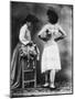 Lady Tries on a Corset While Another Woman Waits with Another One-null-Mounted Photographic Print