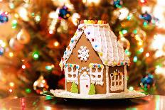 Homemade Christmas Gingerbread House Displayed on a Table. Christmas Tree Lights in the Background.-Leena Robinson-Photographic Print