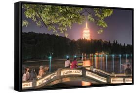 Leifeng Pagoda with Visitors Sitting on Railings of an Illuminated Stone Arch Bridge at West Lake-Andreas Brandl-Framed Stretched Canvas