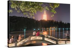 Leifeng Pagoda with Visitors Sitting on Railings of an Illuminated Stone Arch Bridge at West Lake-Andreas Brandl-Stretched Canvas