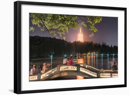 Leifeng Pagoda with Visitors Sitting on Railings of an Illuminated Stone Arch Bridge at West Lake-Andreas Brandl-Framed Photographic Print