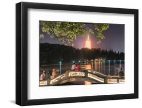 Leifeng Pagoda with Visitors Sitting on Railings of an Illuminated Stone Arch Bridge at West Lake-Andreas Brandl-Framed Photographic Print