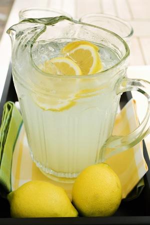 Lemonade. Glass jug with lemonade and lemon slices on a white