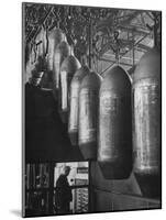 Line of 500 lbs Bombs Jiggling Along on Overhead Conveyor Hooks Abover Worker-Andreas Feininger-Mounted Photographic Print