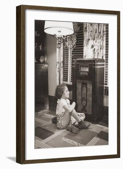 Little Girl Smiles as She Enjoys a Radio Program in the 1930s-null-Framed Photo