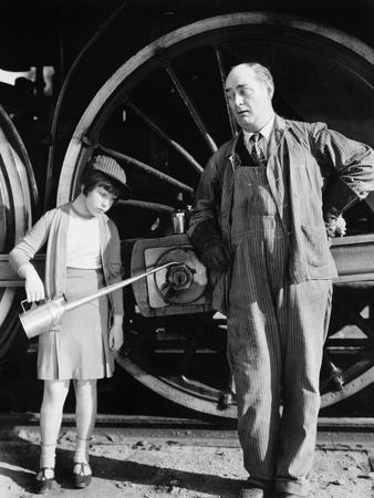 https://imgc.allpostersimages.com/img/posters/little-girl-with-an-oil-can-standing-next-to-a-locomotive-and-the-engine-driver_u-L-Q1BW5ZY0.jpg?artPerspective=n