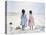 Little Girls on Beach with Flowers and Toy Sail Boat-Nora Hernandez-Stretched Canvas