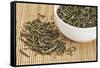 Loose Leaf Sencha Green Tea in a White China Cup and Spilled over Bamboo Mat-PixelsAway-Framed Stretched Canvas