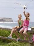 Two Girls Feeding Chips to a Seagull at the Beach-Louise Hammond-Stretched Canvas