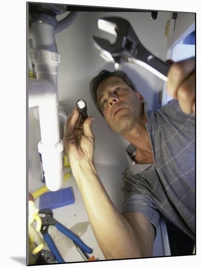 Low Angle View of a Young Man Checking the Plumbing with a Flashlight-null-Mounted Photographic Print