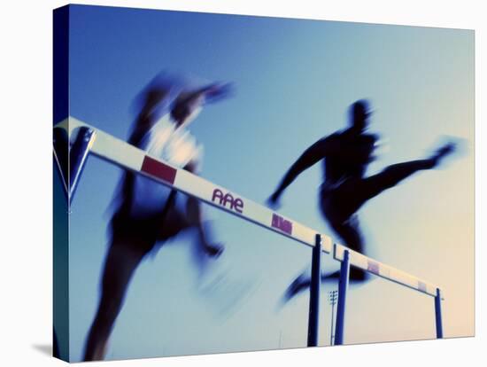 Low Angle View of Athletes Jumping over Hurdles-null-Stretched Canvas