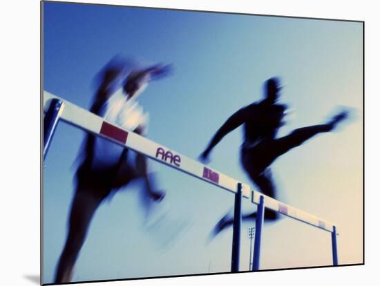 Low Angle View of Athletes Jumping over Hurdles-null-Mounted Photographic Print