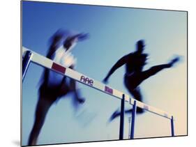 Low Angle View of Athletes Jumping over Hurdles-null-Mounted Photographic Print