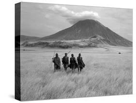 Maasai Warriors Stride across Golden Grass Plains at Foot of Ol Doinyo Lengai, 'Mountain of God'-Nigel Pavitt-Stretched Canvas