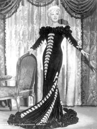 'Mae West standing in Black Long Gown with Arm's Open' Photo - Movie