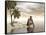 Male Homo Erectus Sitting Alone on a Beach Island Next to Coconuts-null-Framed Stretched Canvas