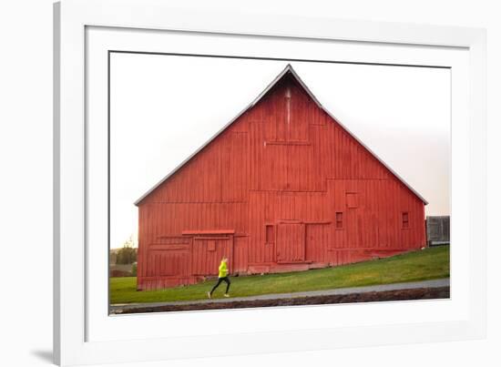 Male Runner Runs Along A Gravel Trail In Front Of Bright Red Barn In UI Arboretum In Moscow, Idaho-Ben Herndon-Framed Photographic Print