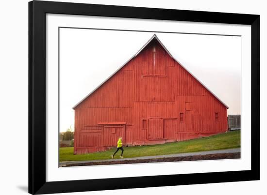 Male Runner Runs Along A Gravel Trail In Front Of Bright Red Barn In UI Arboretum In Moscow, Idaho-Ben Herndon-Framed Photographic Print