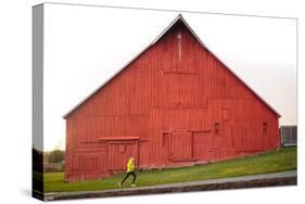 Male Runner Runs Along A Gravel Trail In Front Of Bright Red Barn In UI Arboretum In Moscow, Idaho-Ben Herndon-Stretched Canvas