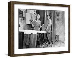 Man and Woman Standing in a Kitchen While She is Ironing His Pants and He is Behind a Curtain-null-Framed Photo