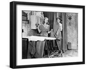 Man and Woman Standing in a Kitchen While She is Ironing His Pants and He is Behind a Curtain-null-Framed Photo