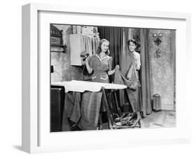 Man and Woman Standing in a Kitchen While She is Ironing His Pants and He is Behind a Curtain-null-Framed Photo