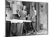 Man and Woman Standing in a Kitchen While She is Ironing His Pants and He is Behind a Curtain-null-Mounted Photo