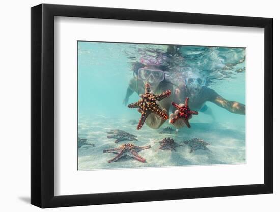 Man and woman with scuba masks showing starfish swimming underwater in the exotic lagoon-Roberto Moiola-Framed Photographic Print